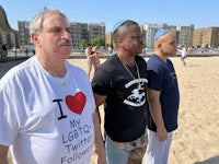 three men standing on a beach